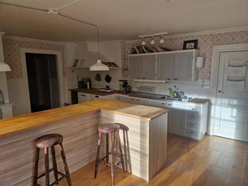 a kitchen with white cabinets and two bar stools at Myskje Gård in Myssje