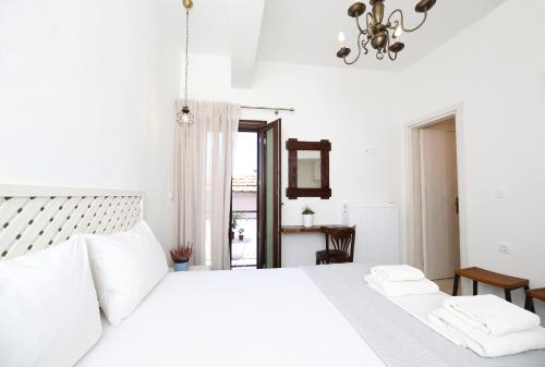 a white bedroom with a white bed with two white towels at Marousos Central Guesthouse in Portariá