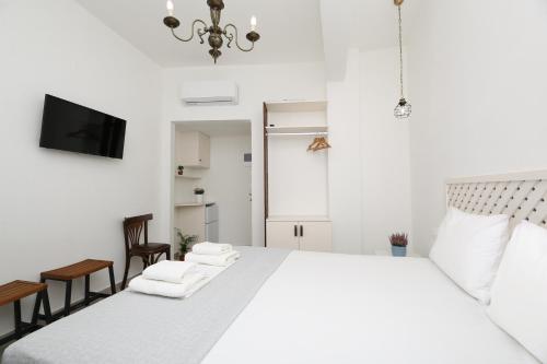 Un dormitorio blanco con una cama grande y un televisor. en Marousos Central Guesthouse, en Portaria