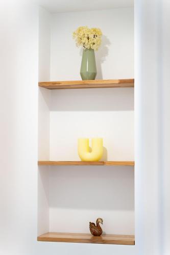 a shelf with a vase of flowers and a candle at Maison Cosy Centre Gare Amiens in Amiens