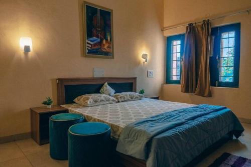 a bedroom with a large bed with two stools at Cozy 3 BHK in the Heart of Ludhiana in Baddowāl