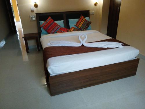 a bedroom with a large bed with white sheets at Joel's River Wood in Pernem