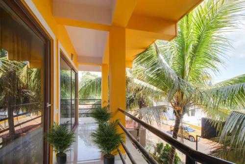 a building with a balcony with palm trees at Joel's River Wood in Pernem