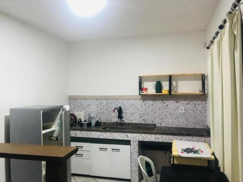 a kitchen with white cabinets and a counter top at Flats do Cordeiro in Cabo Frio