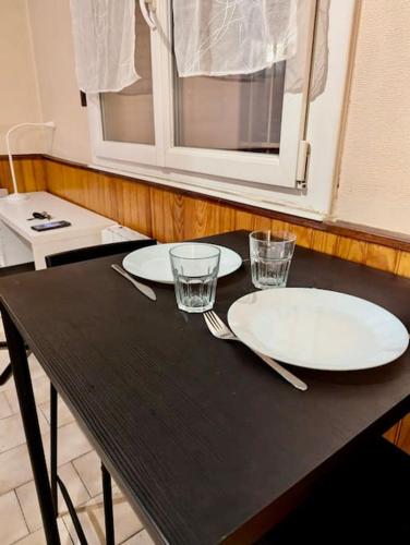 une table noire avec deux assiettes et des verres dans l'établissement Studio Centre avec Parking Gratuit - Calme & Tout Equipé, à Grenoble