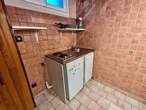 Il comprend une petite cuisine avec un évier et un mur carrelé. dans l'établissement Studio Centre avec Parking Gratuit - Calme & Tout Equipé, à Grenoble