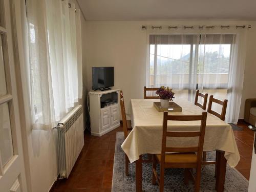 a dining room with a table and a tv at Casa de Casarelhos - Vistas rio - "Gerês" in Geres