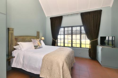 a bedroom with a bed and a large window at Grace Courtyard Cottage in Bredasdorp