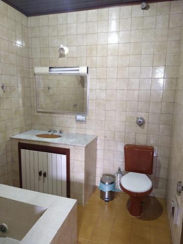 a bathroom with a toilet and a sink and a mirror at Pousada Casa de Buzios in Búzios