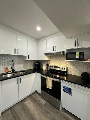 a kitchen with white cabinets and a black stove top oven at The Urban Nest in Calgary