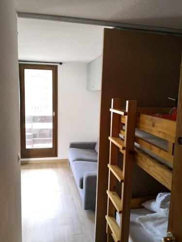 Cette petite chambre comprend des lits superposés et un canapé. dans l'établissement MyHome - Plein Soleil 31 - Charmant studio 4 personnes au pied des pistes - Val Claret, à Tignes