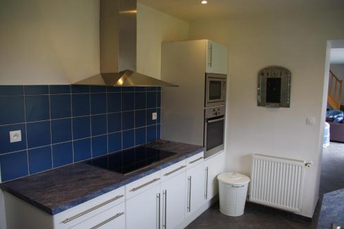 a kitchen with white cabinets and blue tile on the wall at Villa Audresselles in Ambleteuse