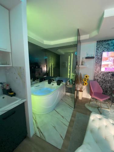 a bathroom with a large tub and a pink chair at Love spa apartman in Banja Koviljača
