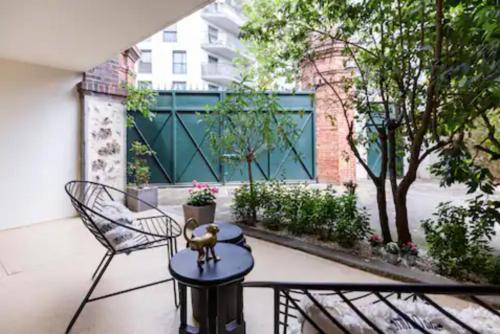 a patio with two chairs and a table and a fence at Ecrin de verdure aux portes de Paris in Arcueil