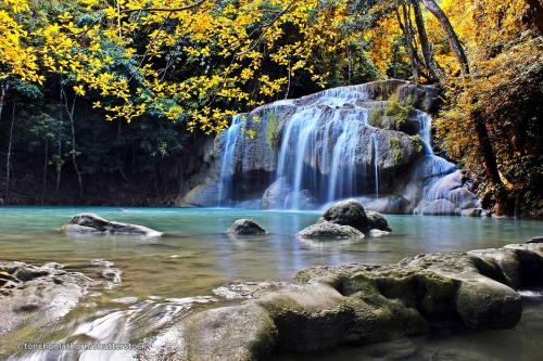 a waterfall in the middle of a river with rocks at The Bridge Residence Hotel in Kanchanaburi