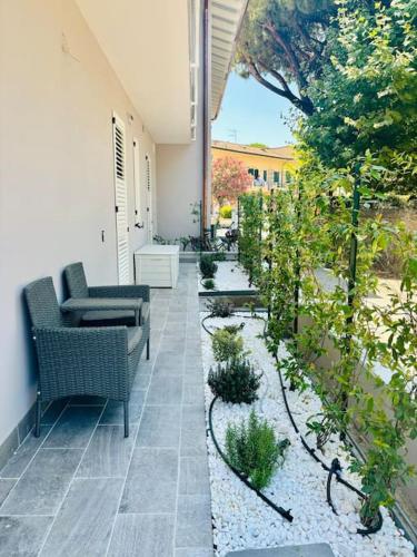 an outdoor patio with two chairs and plants at Maison Jula Confort, Relax e Libertà, Cinquale in Cinquale