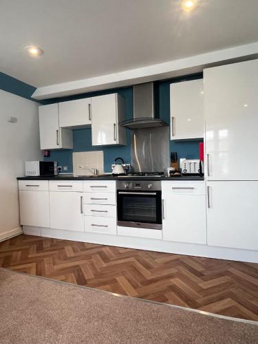 a kitchen with white cabinets and a stove at Jasper Apartment in Lyme Regis
