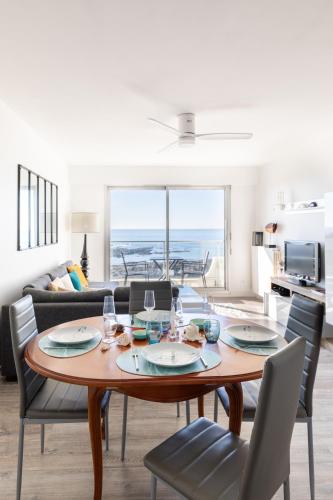 une salle à manger avec une table et des chaises et un salon dans l'établissement Appartement d'exception avec vue plongeante sur l'Océan - Elégance et évasion, à Les Sables-dʼOlonne