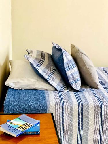 a bed with pillows and a book on a table at HOTEL PLENITUD JARDÍN - Transporte, Tours y Más in Jardin