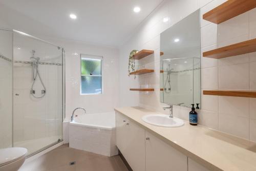 a white bathroom with a sink and a shower at 4-18 Peregian Esplanade, Peregian Beach QLD 4573 in Peregian Beach
