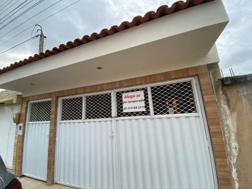 eine weiße Garagentür mit Schild drauf in der Unterkunft Casa de praia em Tamandaré - Carneiros in Tamandaré