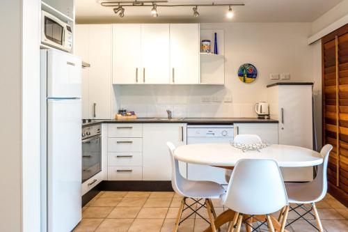 a kitchen with a table and white appliances at Onetangi Beach Apartments in Onetangi