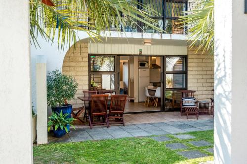 a patio with chairs and a table and a kitchen at Onetangi Beach Apartments in Onetangi