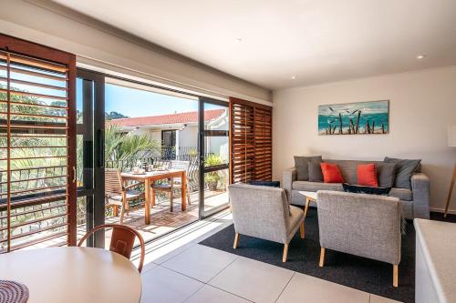 a living room with a couch and a table and chairs at Onetangi Beach Apartments in Onetangi