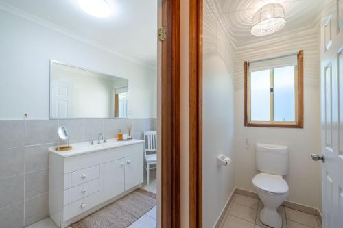 a bathroom with a toilet and a sink and a mirror at Wanda Up, 80 Randall Dr - spectacular views, aircon and Wi-Fi in Salamander Bay