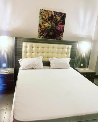 ein Schlafzimmer mit einem großen weißen Bett mit einem großen Kopfteil in der Unterkunft CosyServives in Grand Médina