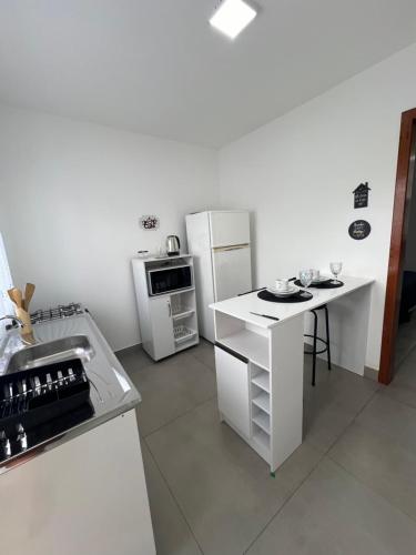 a white kitchen with a refrigerator and a table at Casa Fabluys 3 in Florianópolis