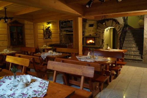 a restaurant with wooden tables and chairs and a fireplace at Willa Tatrzański Zomecek in Kościelisko