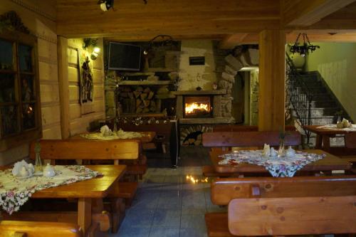 a restaurant with wooden tables and a fireplace at Willa Tatrzański Zomecek in Kościelisko
