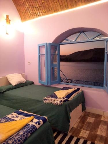ein Zimmer mit zwei Betten und einem großen Fenster in der Unterkunft hooly nubian in Assuan