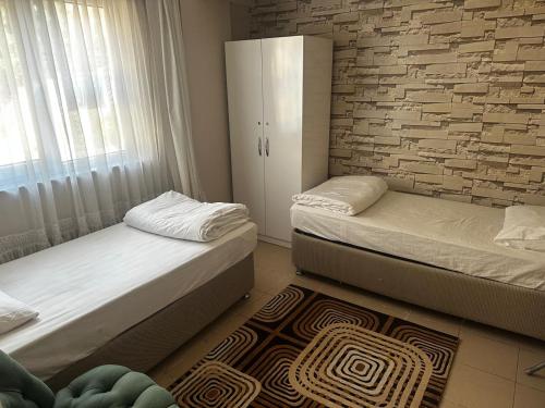 KarabükSafranbolu apartments的一间卧室，有两张床和一堵砖墙