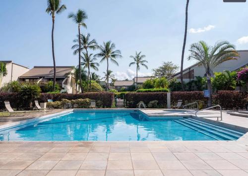 a swimming pool in a resort with palm trees at Ho'omaha - Serene Kihei Condo in Maui Kamaole for Ocean Views and Relaxation in Wailea