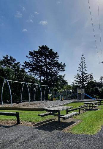 a park with three picnic tables and a playground at Urenui Beach Camp in Urenui