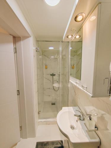 a white bathroom with a sink and a shower at Apartman Premijer 2 in Čukarica