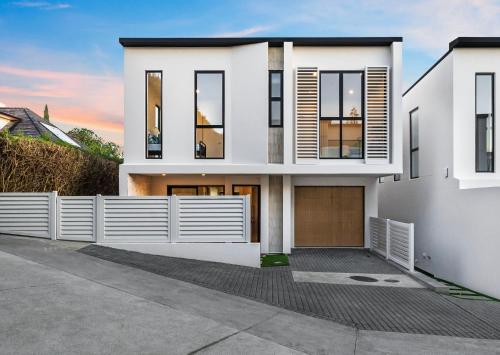 a white house with a fence in front of it at Elegant New Luxury Retreat in Remuera in Auckland