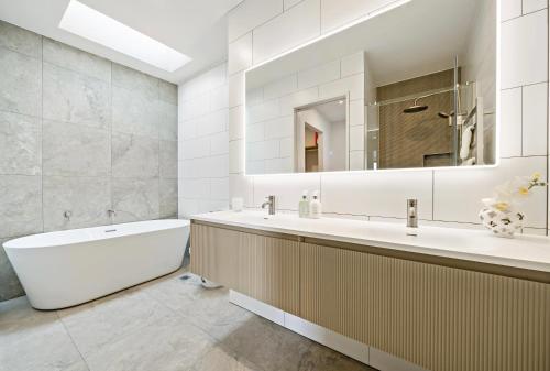 a bathroom with a tub and a large mirror at Elegant New Luxury Retreat in Remuera in Auckland