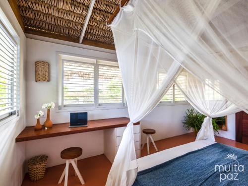 a bedroom with a bed and a desk and windows at Casa Mais Amor in Atins