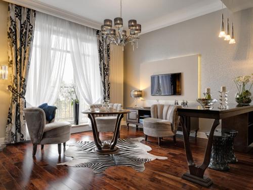 a living room with a table and chairs and a television at Rezydencja Luxury Hotel Bytom Piekary Śląskie in Piekary Śląskie