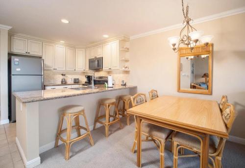 a kitchen with a table and chairs and a refrigerator at Ho'omaha - Serene Kihei Condo in Maui Kamaole for Ocean Views and Relaxation in Wailea