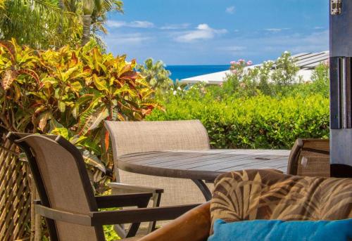 a wooden table and chairs on a patio with the ocean at Ho'omaha - Serene Kihei Condo in Maui Kamaole for Ocean Views and Relaxation in Wailea