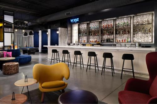 a bar with a yellow chair and tables and chairs at Aloft Orlando at SeaWorld in Orlando