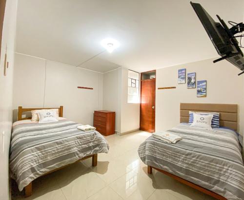 a bedroom with two beds and a tv on the wall at QAIPU HOTEL in Puquio