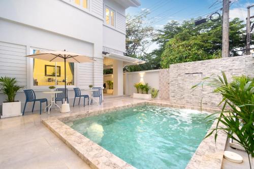 a swimming pool with chairs and an umbrella next to a house at Seven Heaven Patong Villa in Patong Beach