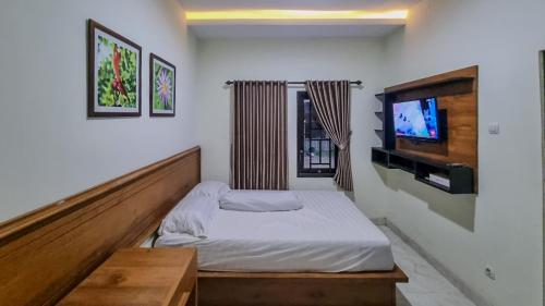 a small bedroom with a bed and a television at Balmoral House Ambarukmo in Yogyakarta