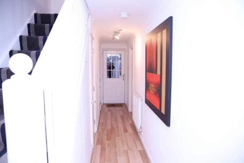 a hallway with a staircase and a painting on the wall at StayNorwich 69G - Hush View House in Romford