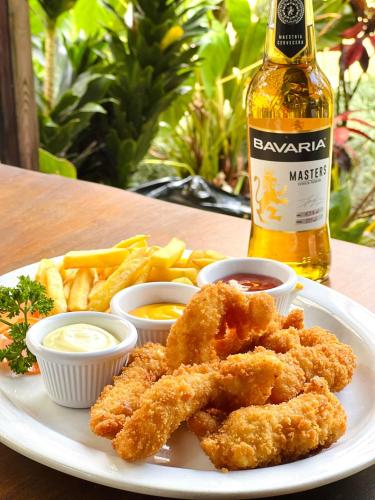 a plate with chicken tenders and french fries and a bottle of beer at Ávita Lodge in Quesada
